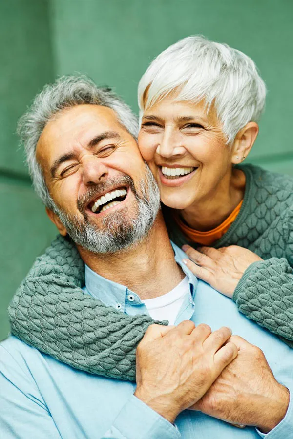 Liquid-Lipo-Treatment A mature couple embrace on a green porch smiling. Get Liquid Lipo treatment from Healthy Aging Medical Centers of New Jersey in Northern New Jersey.