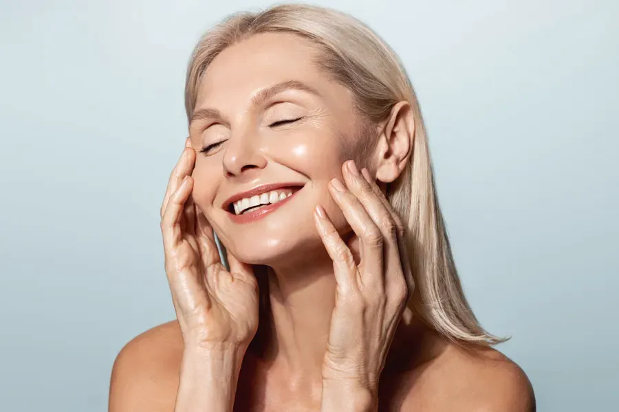 PRP-Facelift-Facial-Doctor A beautiful mature blonde woman touches her face, happy with her PRP facelift and facial injections from Healthy Aging Medical Centers of New Jersey in Northern New Jersey.