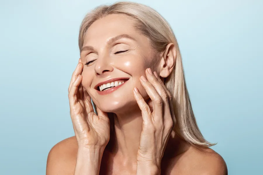 Radiofrequency-Microneedling-for-Face-and-Jawline-Clinic A woman with a smooth, tight jawlline smiles and holds her face. Schedule Radiofrequency Microneedling for Face and Jawline Skin Treatment from Healthy Aging Medical Centers of New Jersey in Northern New Jersey.